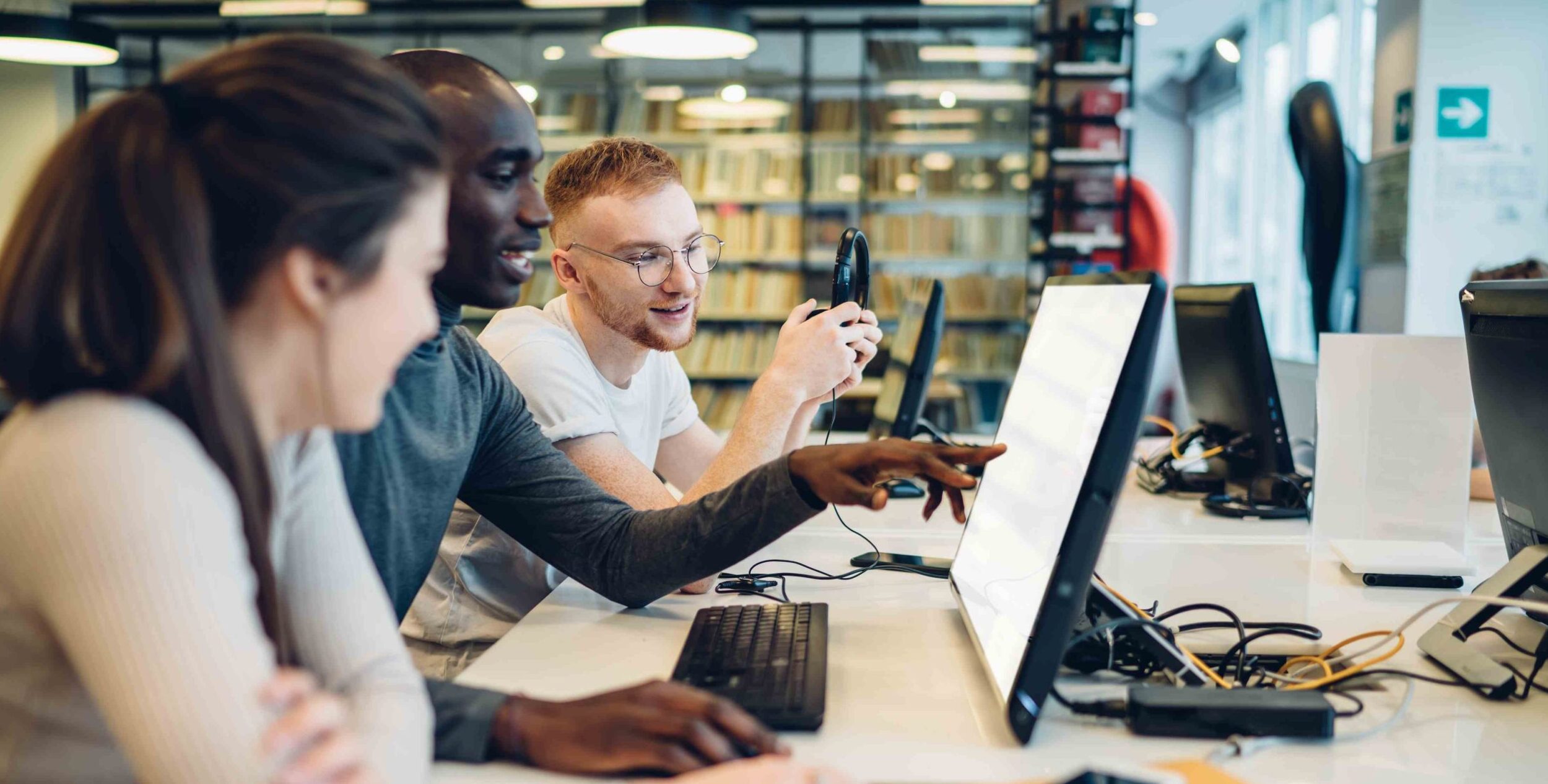 Interested multiracial students using computer while studying in library